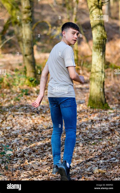 Teenage Caucasian Boy Walking Away Through Woodland On A Warm Spring