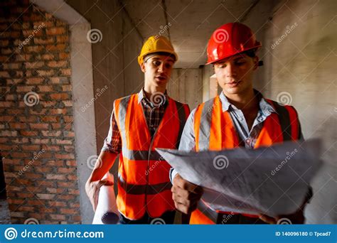 Construction Manager And Engineer Dressed In Orange Work Vests And