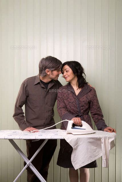 A Couple Kissing Whilst Ironing[11016015304]の写真素材・イラスト素材｜アマナイメージズ