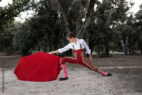 Side View Of Slim Male Bullfighter In Red Pants And White Shirt Holding