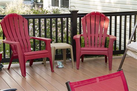Two Red Chairs Sitting On Top Of A Wooden Deck Next To A Table And Chair