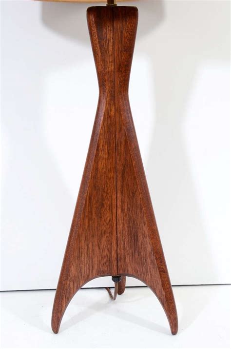 The lamp has a brass cap finial and harp. Mid Century Wood Tripod Base Table Lamp at 1stdibs