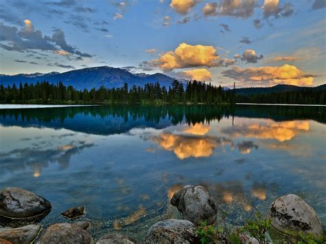 Lake Shore With Rocks Pine Trees Mountains Sky Dark Cloud Reflection