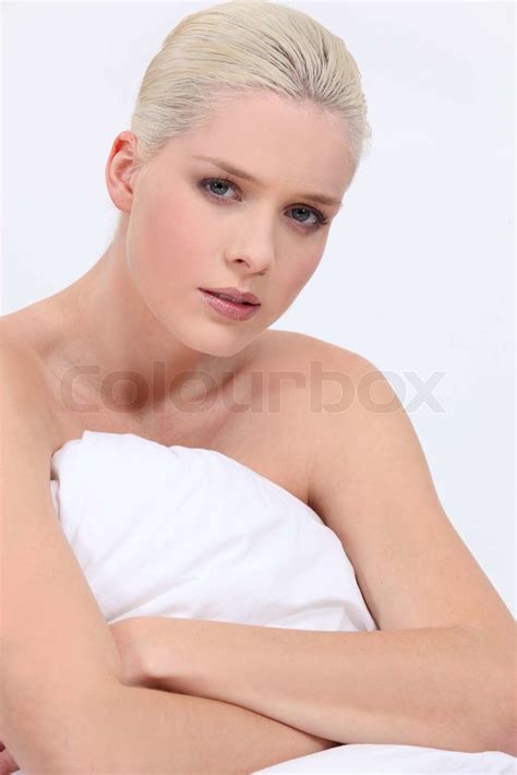 Blonde Woman Naked Sitting On Bed With A Neutral Face Expression