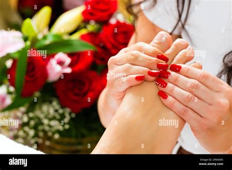 Woman Receiving Feet Massage With Massage In A Day Spa Lots Of Flowers