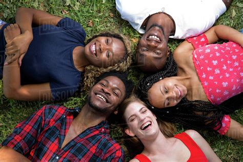 Group Of Friends Lying On The Grass Laughing Stock Photo Dissolve
