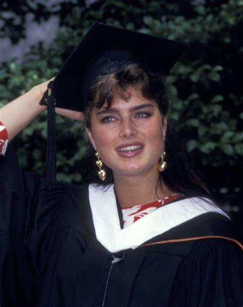 A Woman Wearing A Graduation Gown And Holding Her Cap Over Her Head