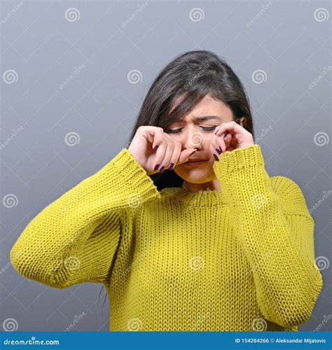 Woman Crying And Wiping Tears Against Gray Background Stock Photo
