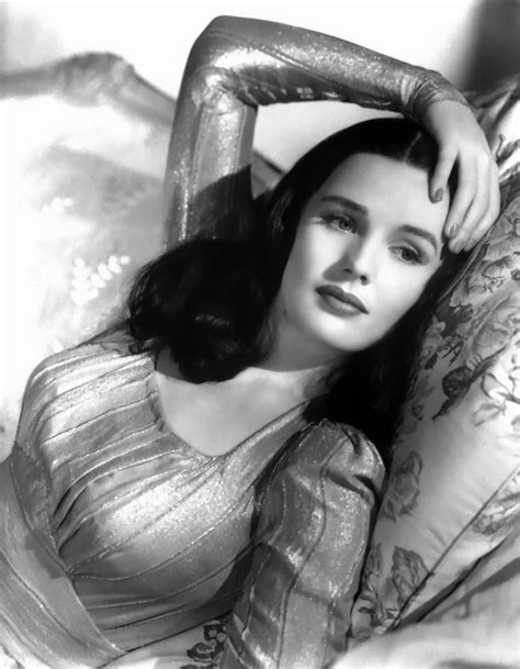 a black and white photo of a woman laying on a bed with her arms behind her head