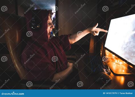 Emotional Gamer Sitting At Home At Computer At Night Looking Into The