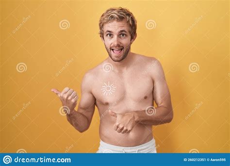 Caucasian Man Standing Shirtless Wearing Sun Screen Pointing To The