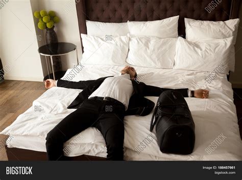 Exhausted Businessman Resting On Bed After Long Air Flight Jet Lag Man In Business Suit Lying