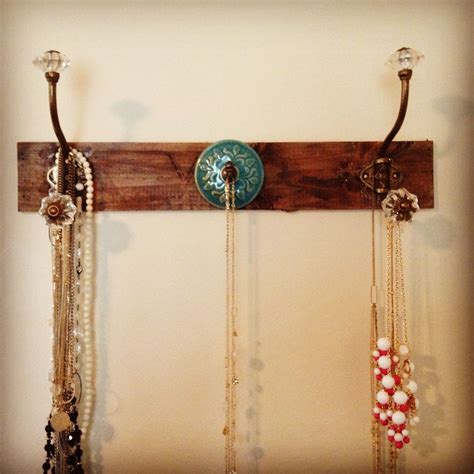 Three Necklaces Are Hanging On A Wooden Rack With Beads And Chains