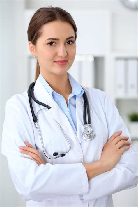 Young Brunette Female Doctor Standing With Arms Crossed And Smiling At