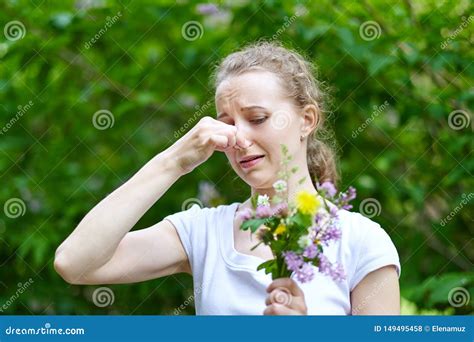 Allergy Woman Squeezed Her Nose With Hand So As Not To Sneeze From The Pollen Of Flowers Stock