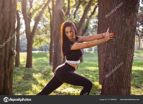 sexy chica estirando isquiotibiales pantorrillas apoyadas Árbol parque fotografía de stock