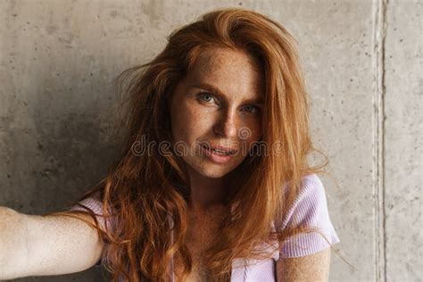 Image Of Redhead Woman Taking Selfie Photo While Posing Near Wall Stock