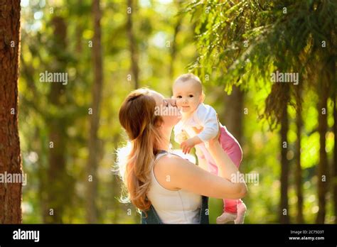 Young Mother Holding Daughter In Her Arms Mom Kisses And Plays With Daughter In The Summer
