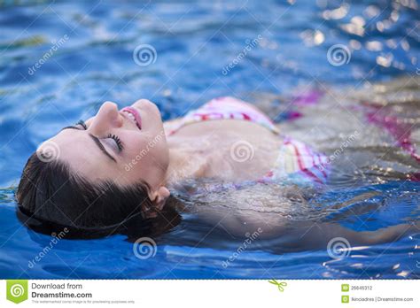 Attractive Young Woman Floating In A Swimming Pool Stock