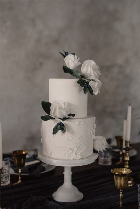 A White Wedding Cake Sitting On Top Of A Table Next To Candles And Other Decorations