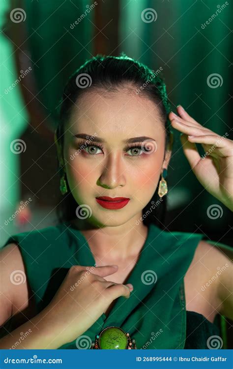 A Beautiful Asian Woman In A Green Dress Is Posing With Her Hands Very