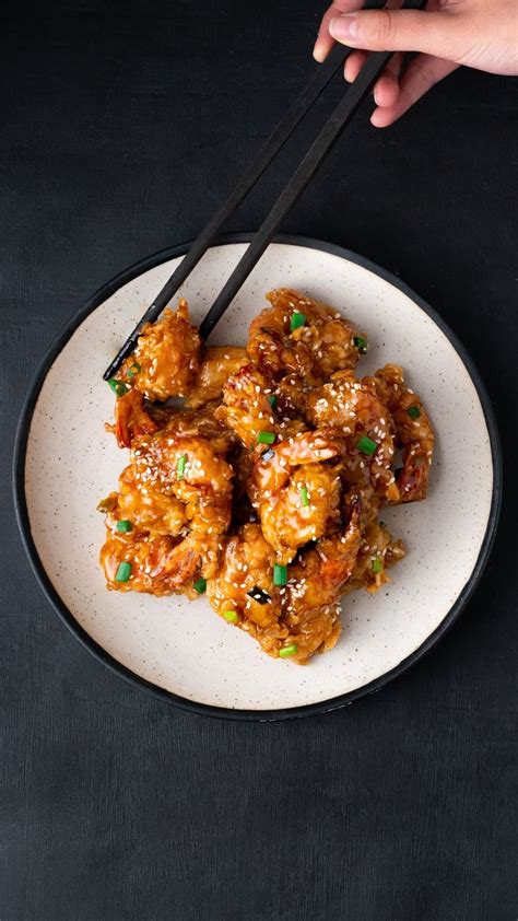 Someone Is Holding Chopsticks Over Some Food On A White Plate With