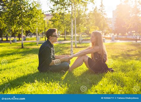 Friendship And Love Concept With A Young Couple Sitting On The Grass