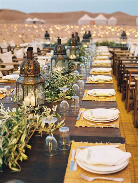 moroccan lantern and greenery centerpieces with woven place mats and white place settings in