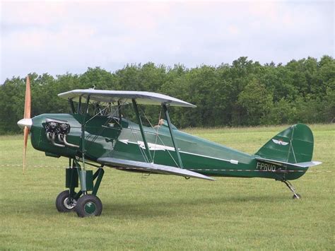 A Small Green Airplane Sitting On Top Of A Lush Green Field