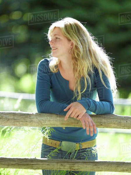 Young Woman Leaning On Fence Stock Photo Dissolve