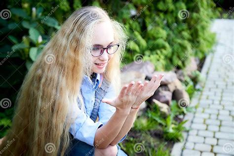 pretty teenage girl 14 16 year old with curly long blonde hair and in glasses in the green park