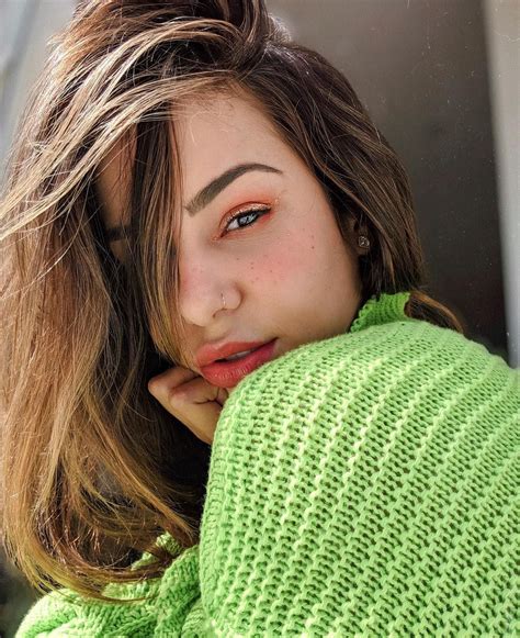 A Woman With Brown Hair And Green Sweater Posing For The Camera While