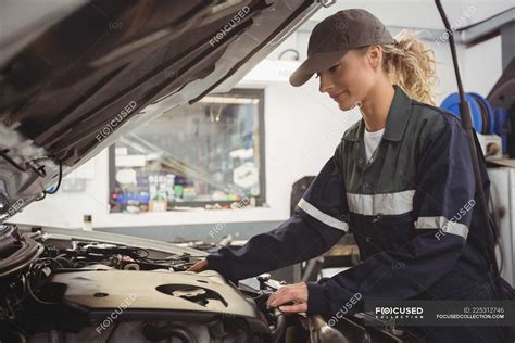 Beautiful Female Mechanic Servicing Car At Repair Garage — Mid Adult