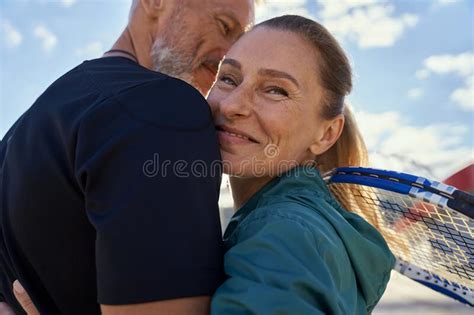 portrait of active mature couple looking happy while embracing each other outdoors ready for