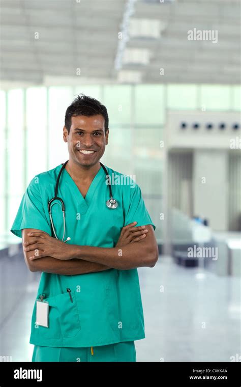 Male Indian Doctor Wearing Green Scrubs In Modern Hospital Stock Photo