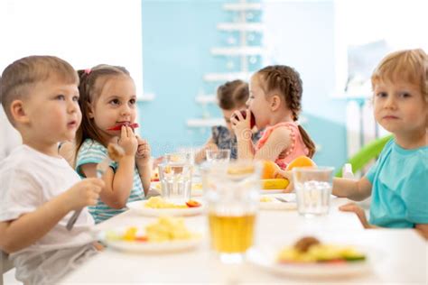 Grupo De Crianças Comendo De Pratos Em Creche Foto De Stock Imagem De