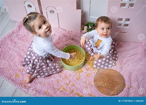 Girls Sit On The Floor In The Kitchen And Play With Dry Pasta Top View Stock Image Image Of