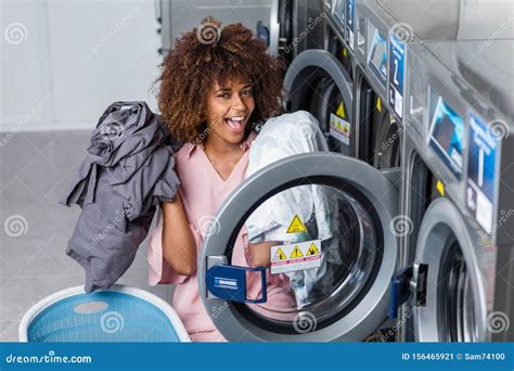 Young African American Woman Washing Her Clothes In A Automatic Laundry