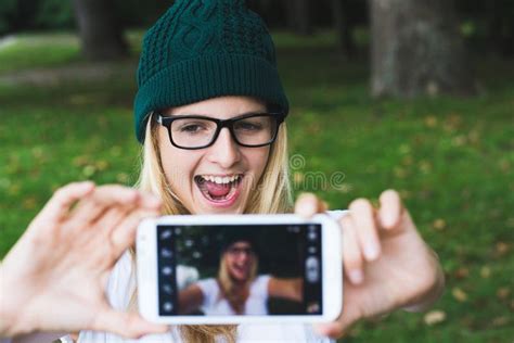 Happy Young Girl Taking Selfie With Cell Phone In Glasses Over White