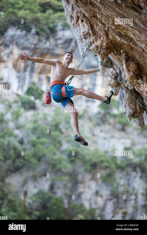 Cheerful Rock Climber Hanging On Rope While Climbing Challenging Route