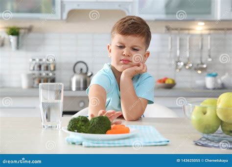 Adorable Little Boy Refusing To Eat Vegetables At Table Stock Image