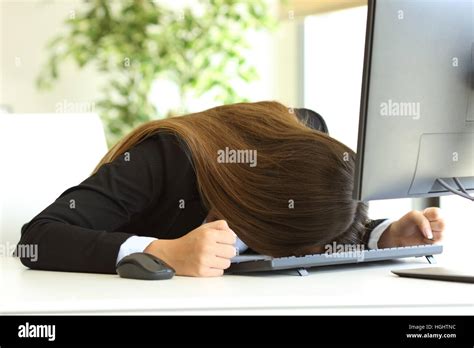 Frustrated Businesswoman Banging Head Against The Desktop In Front Of A