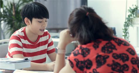 serious asian mother with son doing homework in the living room mom teaches son how to genius