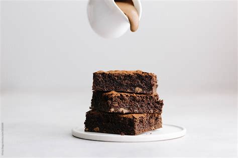 About To Pour Chocolate Ganache Sauce Over Chocolate Brownie Cake Del Colaborador De Stocksy
