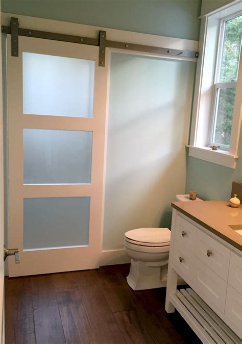 barn door with frosted privacy glass to separate sink and toilet area from the shower space