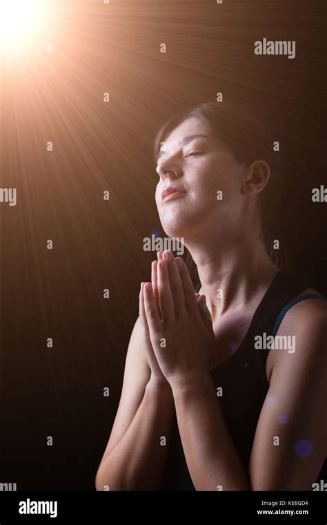 faithful woman praying and smiling in happiness bliss and peace under a divine or celestial