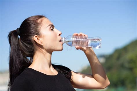 Attractive Sporty Model Drinking Water During Running At The Par Stock