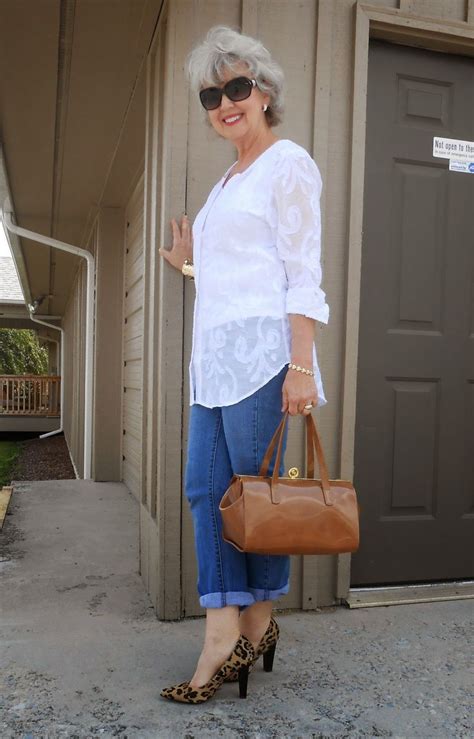 An Older Woman Is Standing On The Sidewalk With Her Hand In Her Pocket