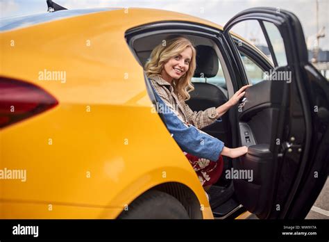 Photo Of Happy Blonde Sitting In Back Seat Of Yellow Taxi With Open