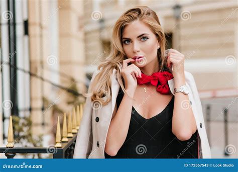 Adorable Fair Haired Woman Wearing Cute Pendant Standing In Front Of